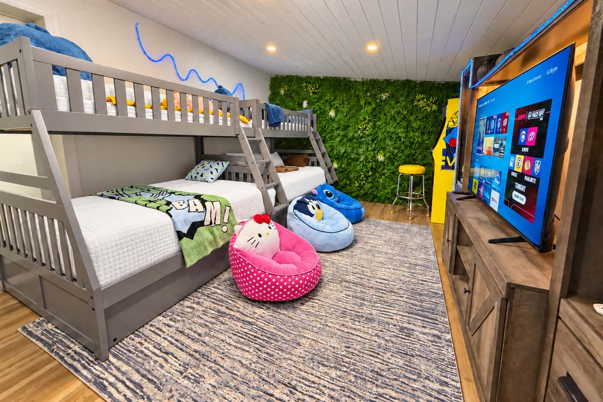 The room everyone will fight over. Bedroom 4 sleeps 9 with two twin-over-full bunks, two twin trundles and a yellow twin sleeper sofa, plus a smart TV, bean bags, Pac-Man arcade and PS5. Sleepover energy, every night.