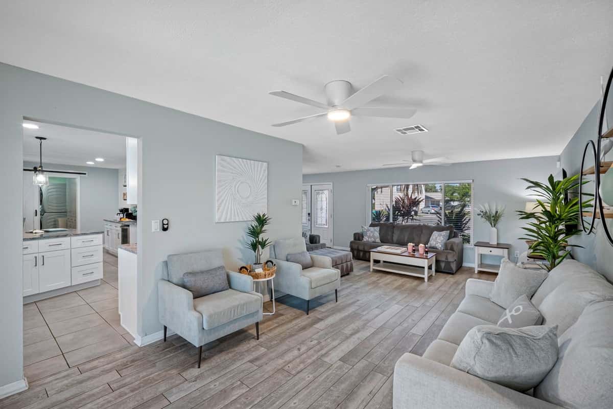 This open-concept living room offers plenty of seating, natural light, and direct access to the pool area for easy indoor-outdoor living.