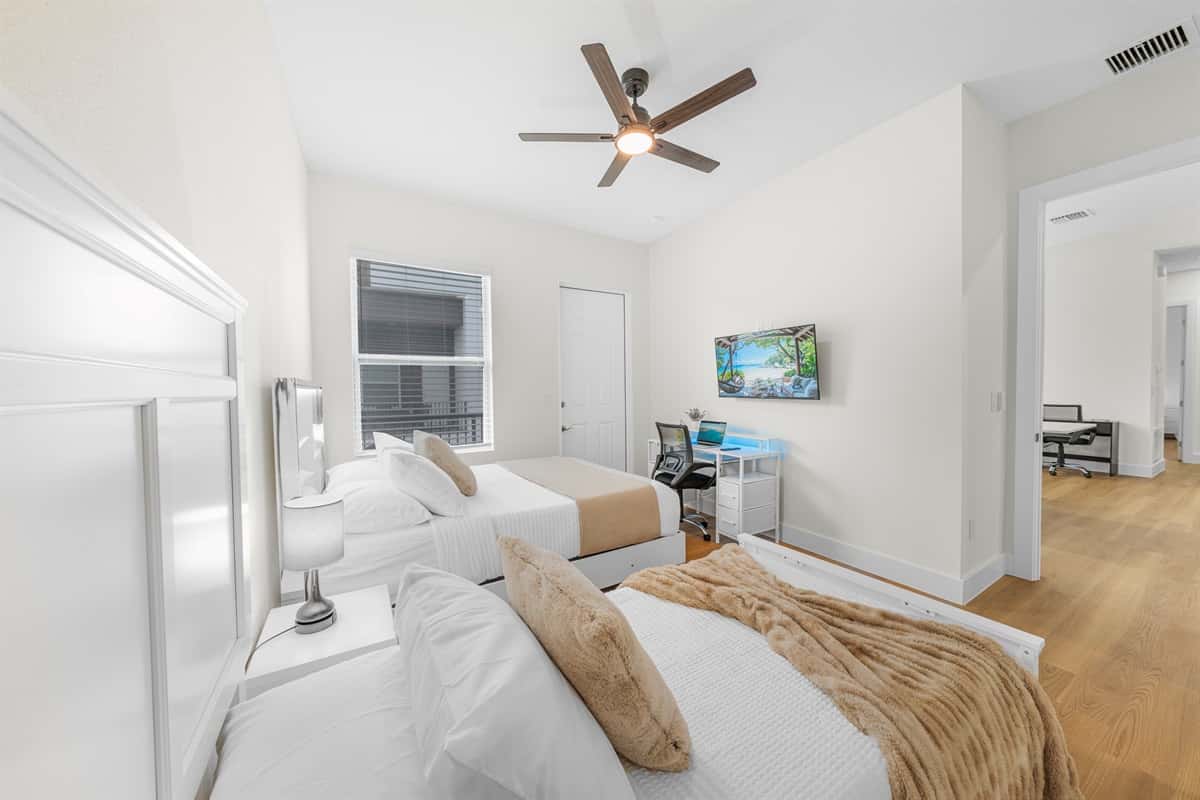 Bedroom with two beds, TV, and workspace—perfect for relaxing or working.
