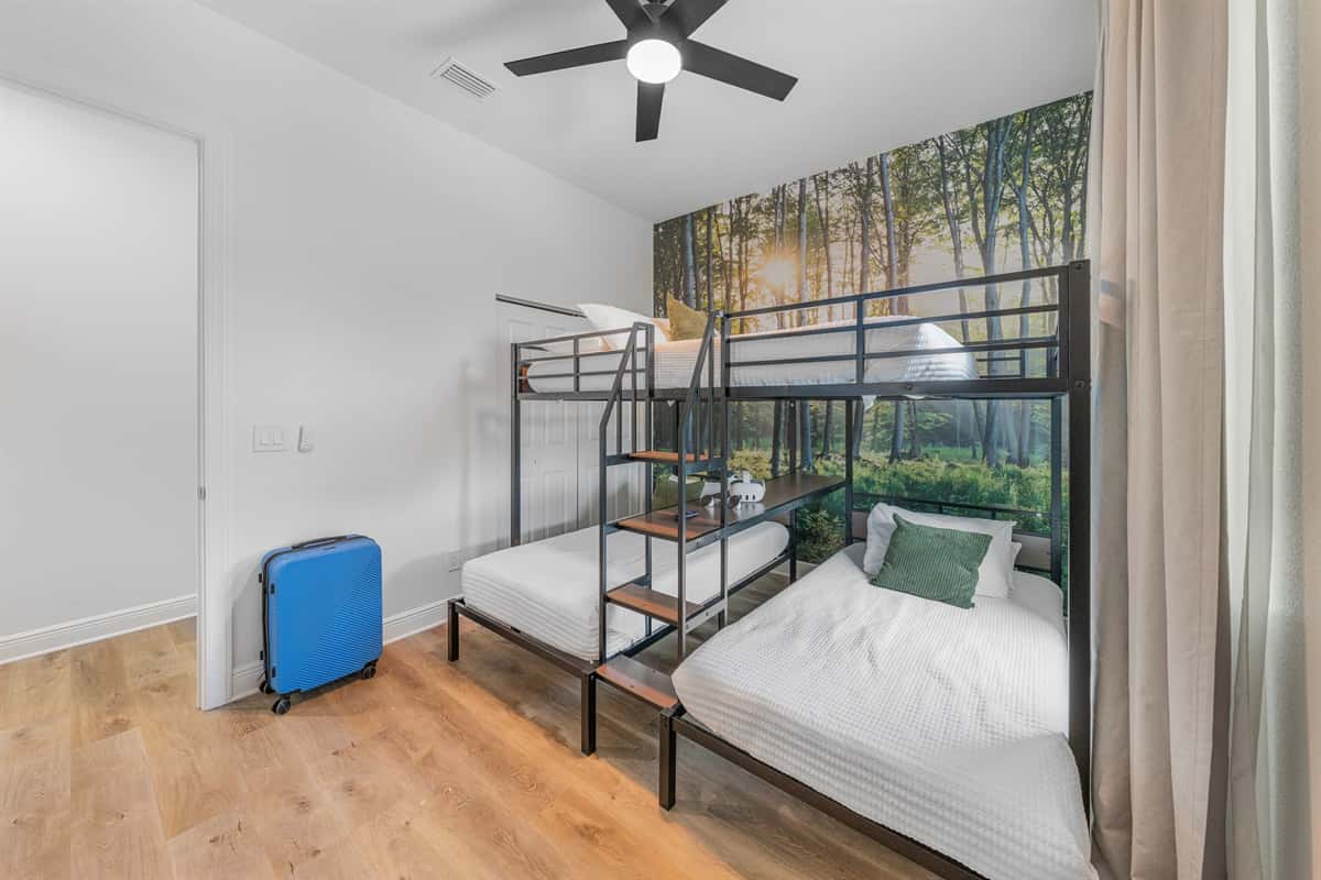 Bright bunk room with multiple beds and a nature-inspired accent wall, perfect for kids or group stays.