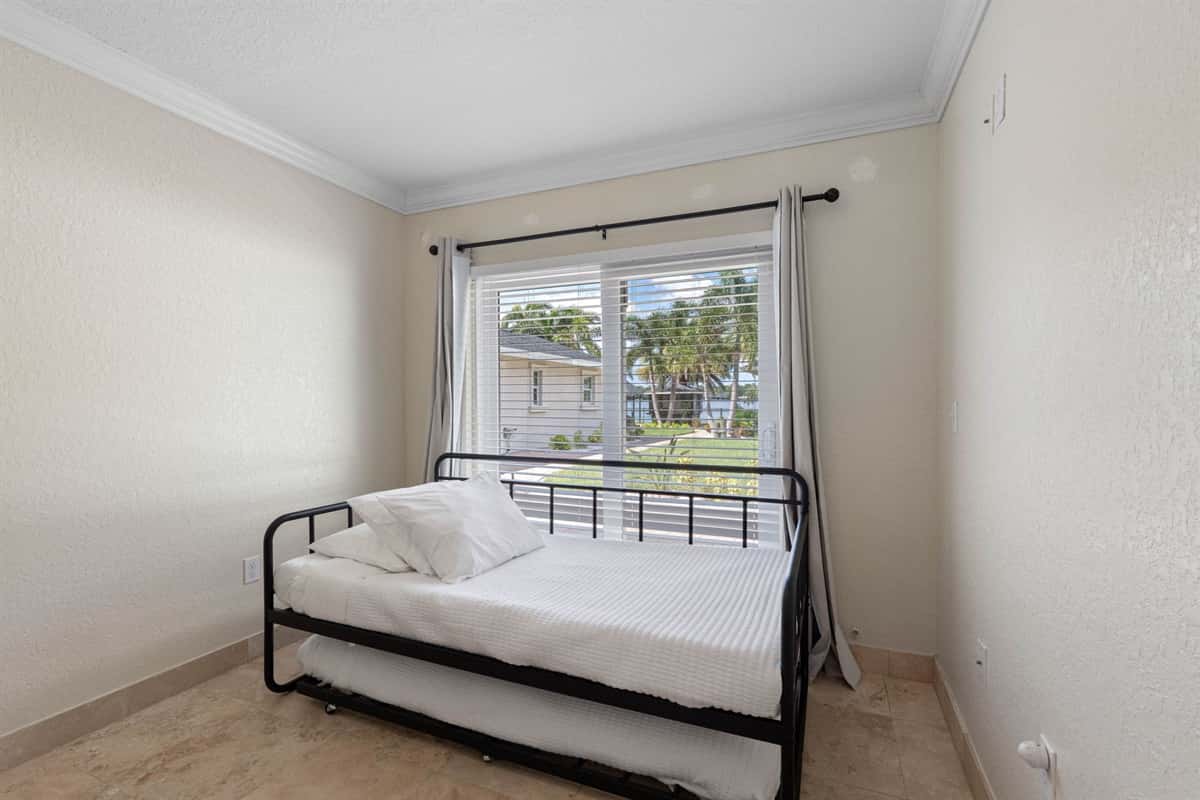 This cozy room features a daybed with trundle, perfect for flexible sleeping arrangements, and a large window with views of the yard and water beyond.