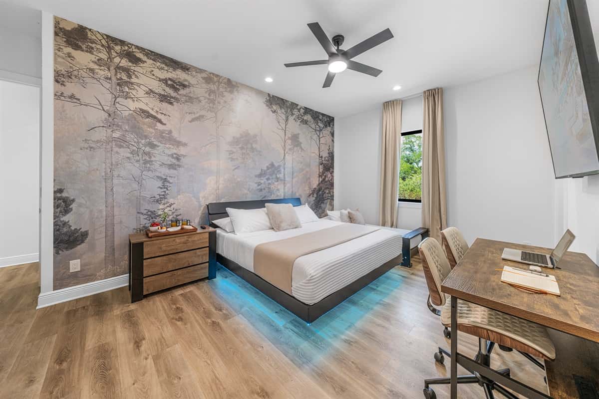 Spacious primary bedroom featuring a king bed, ambient lighting, and a beautiful nature-inspired accent wall.