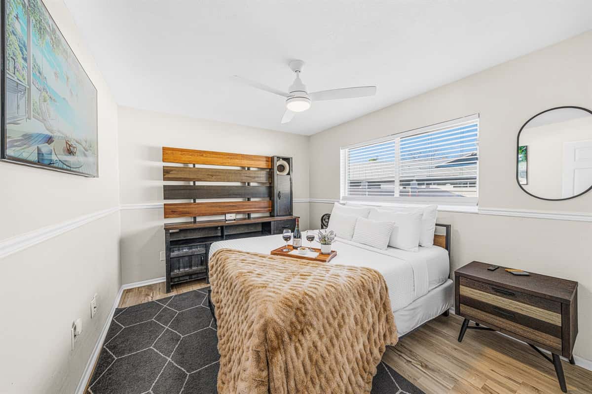 Stylish queen bedroom with modern furnishings, Smart TV, and a comfortable night's sleep.