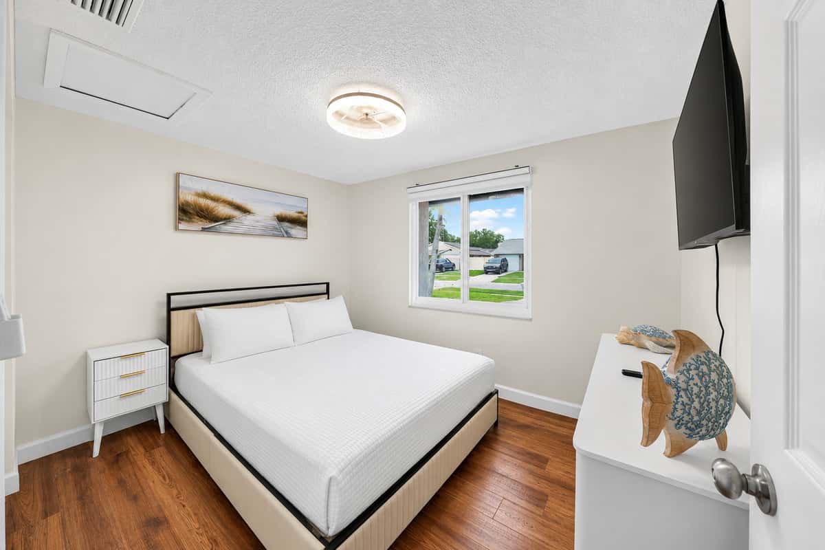 Peaceful guest bedroom featuring a queen bed, Smart TV, and large windows that fill the room with natural light.