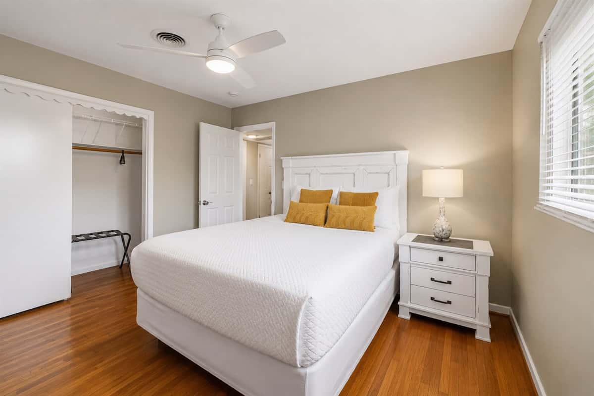 Cozy guest bedroom featuring a comfortable queen bed, soft lighting, and warm wood flooring.
