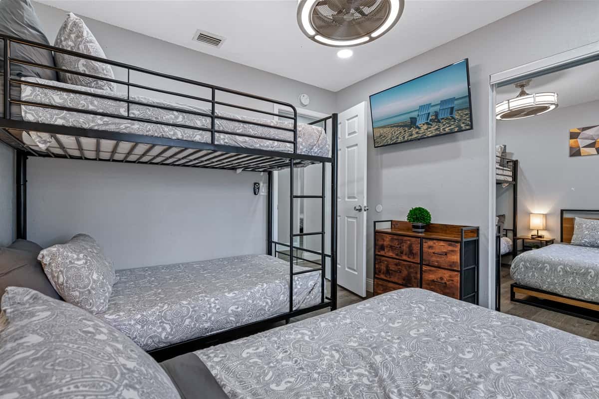 Beautiful bedroom with single bunk bed, queen-sized bed, drawers for storage, and smart TV. Ideal room for a family with kids or a group of friends.