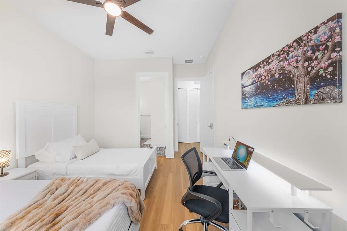 Bright bedroom with two beds, workspace, and modern décor for a relaxing stay.
