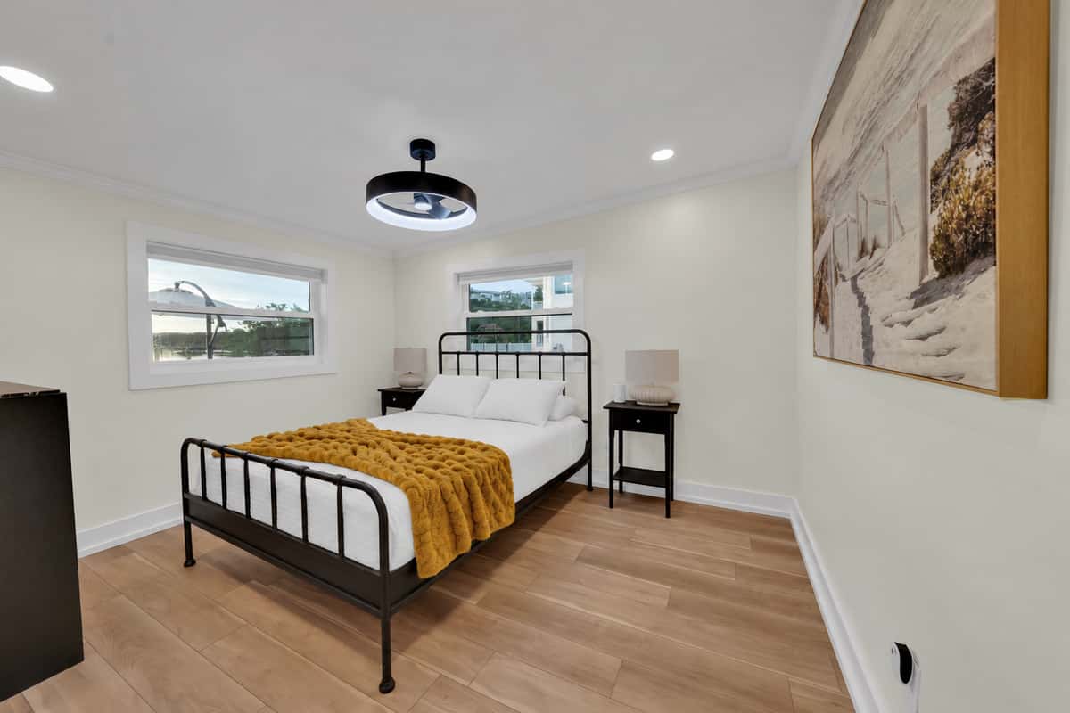 A cozy queen room with a modern touch. A queen bed with a black metal frame, a chunky mustard throw and natural light from two windows. Comfortable, stylish and quiet.