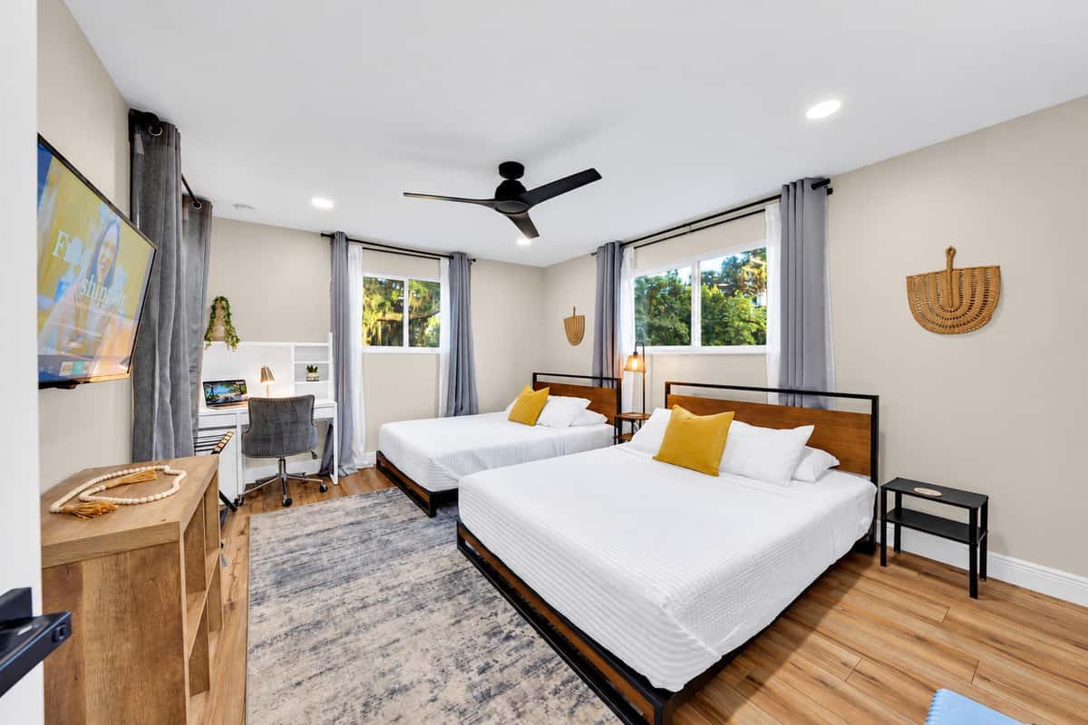 The room that solves the sleeping arrangement. Two full queen beds, generous storage and daylight from the window, with enough floor space that four people unpack without colliding.