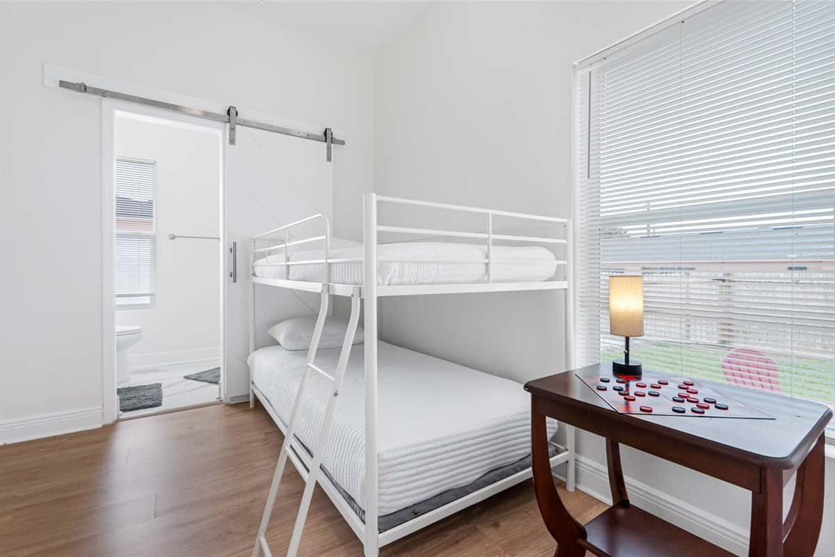 A cozy and well-appointed bunk bedroom that maximizes space without sacrificing comfort. Twin beds, neutral décor, and soft lighting create a calm environment, while the nearby bathroom access makes it especially convenient for families.