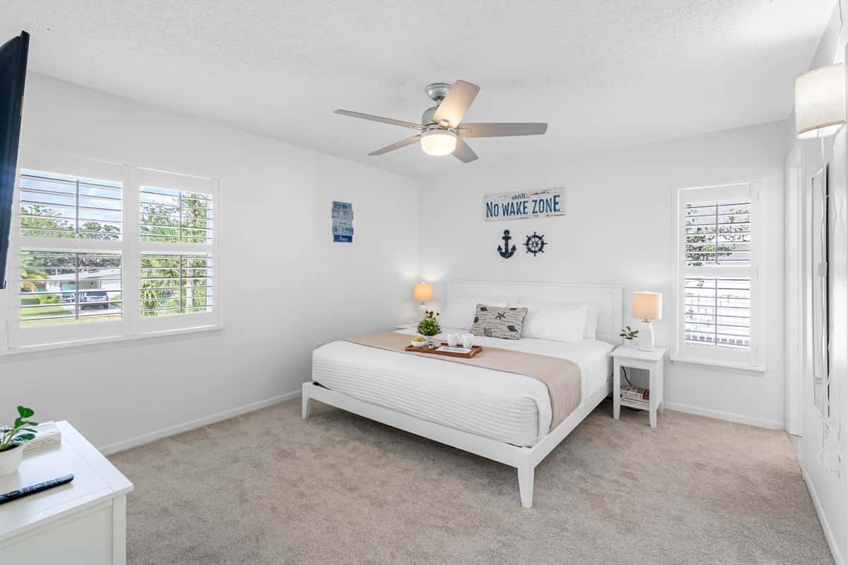 Spacious king suite with soft carpet, coastal décor, and plenty of natural light — your private retreat.