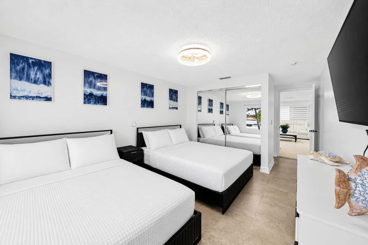 Flexible sleeping space with a king bed, a queen bed, modern furnishings, and easy access to nearby bathrooms.
