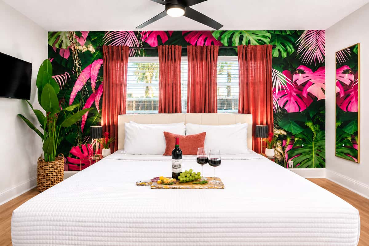 Recharge in the spacious primary bedroom featuring a plush King bed, bold tropical décor, blackout curtains, and a peaceful atmosphere designed for restful nights after a day in the Florida sunshine.