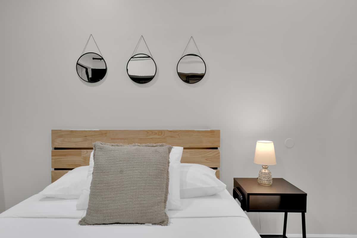 Deep sleep, soft light, no one knocking. Wide bed, warm wood headboard and a bedside lamp for reading, in a quiet corner of the estate where the pool noise never quite reaches.