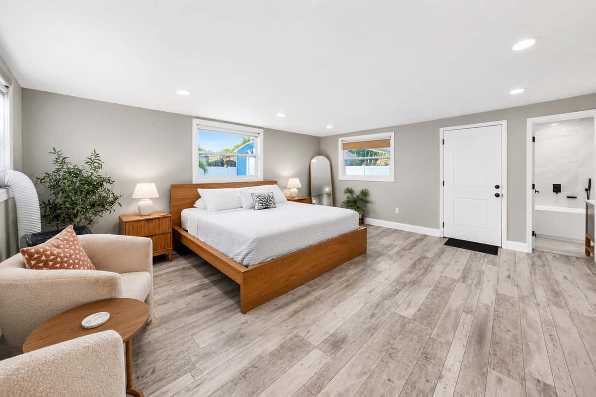 Spacious primary bedroom with a king-size bed, comfortable sitting area, en-suite bathroom access, and abundant natural light.