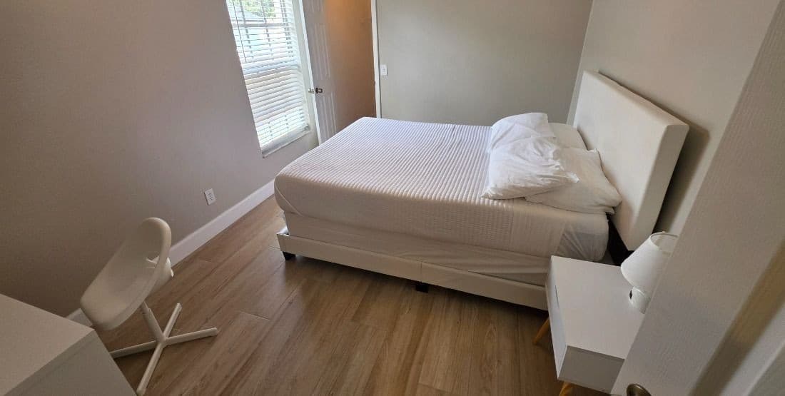 Bright and welcoming bedroom featuring a comfortable bed, modern décor, and plenty of natural light from the large window.