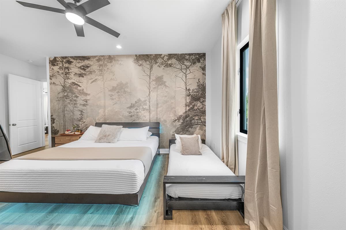 Alternate view of the primary bedroom with workspace, TV, and calming, modern décor.