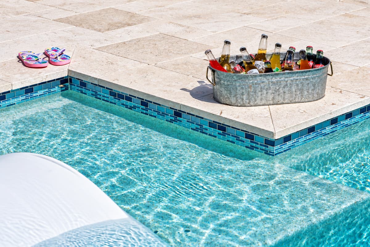 White stone tile, minimalist landscaping, and crisp design make this pool area pop.