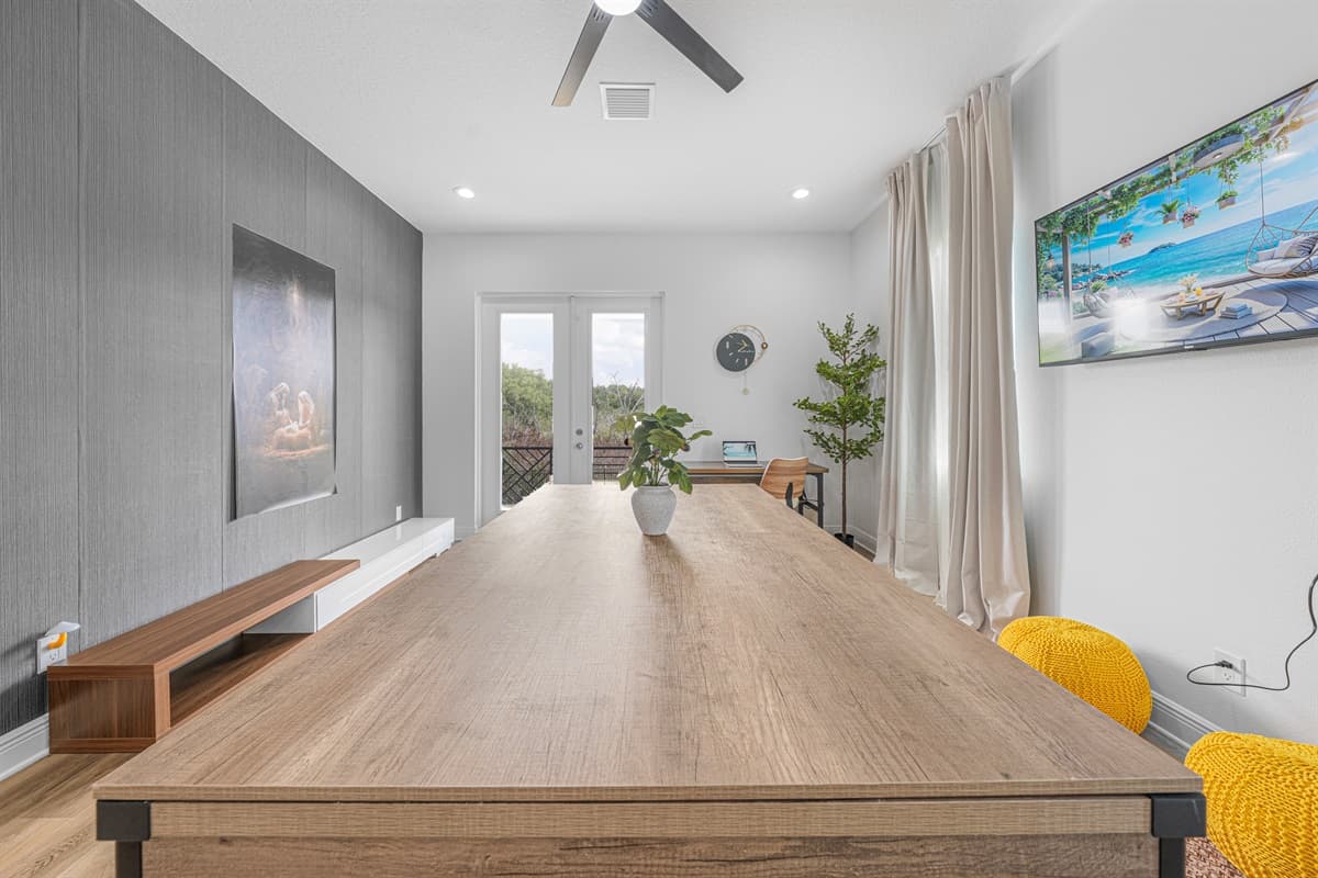 Sleek and modern game area with a long pool table, minimalist design, and a stylish feature wall with mounted TV.