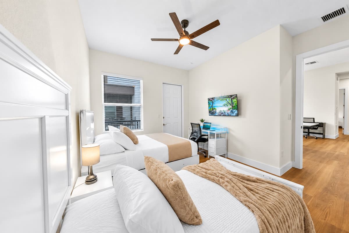 Bedroom with two beds, TV, and workspace—perfect for relaxing or working.
