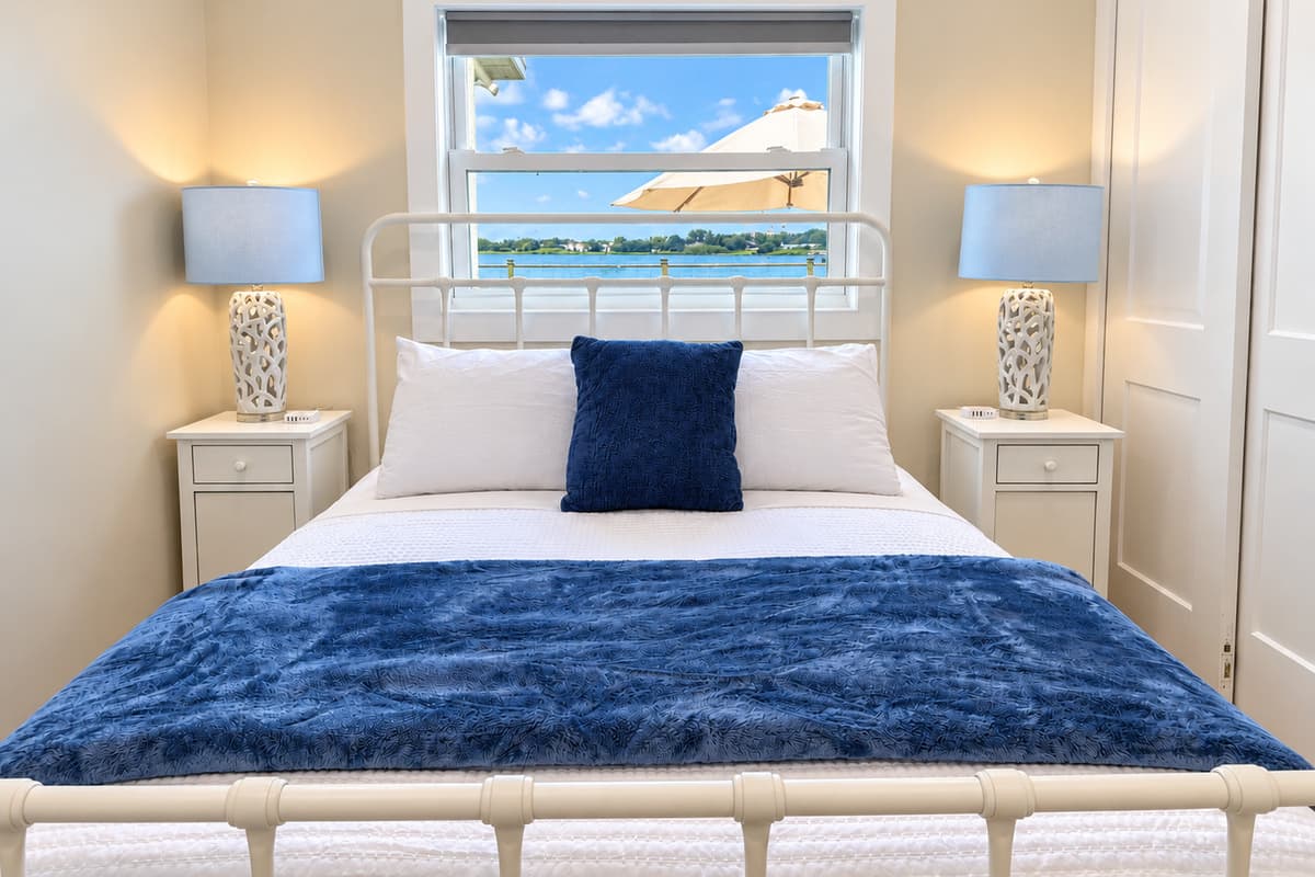 Queen bedroom with a white metal bed frame and smart TV.