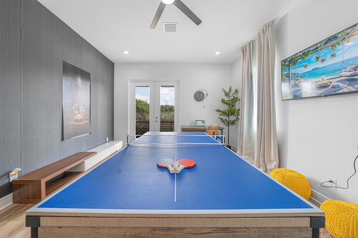 Dedicated game room with a ping pong table, large TV wall, and natural light—great for entertainment and fun.