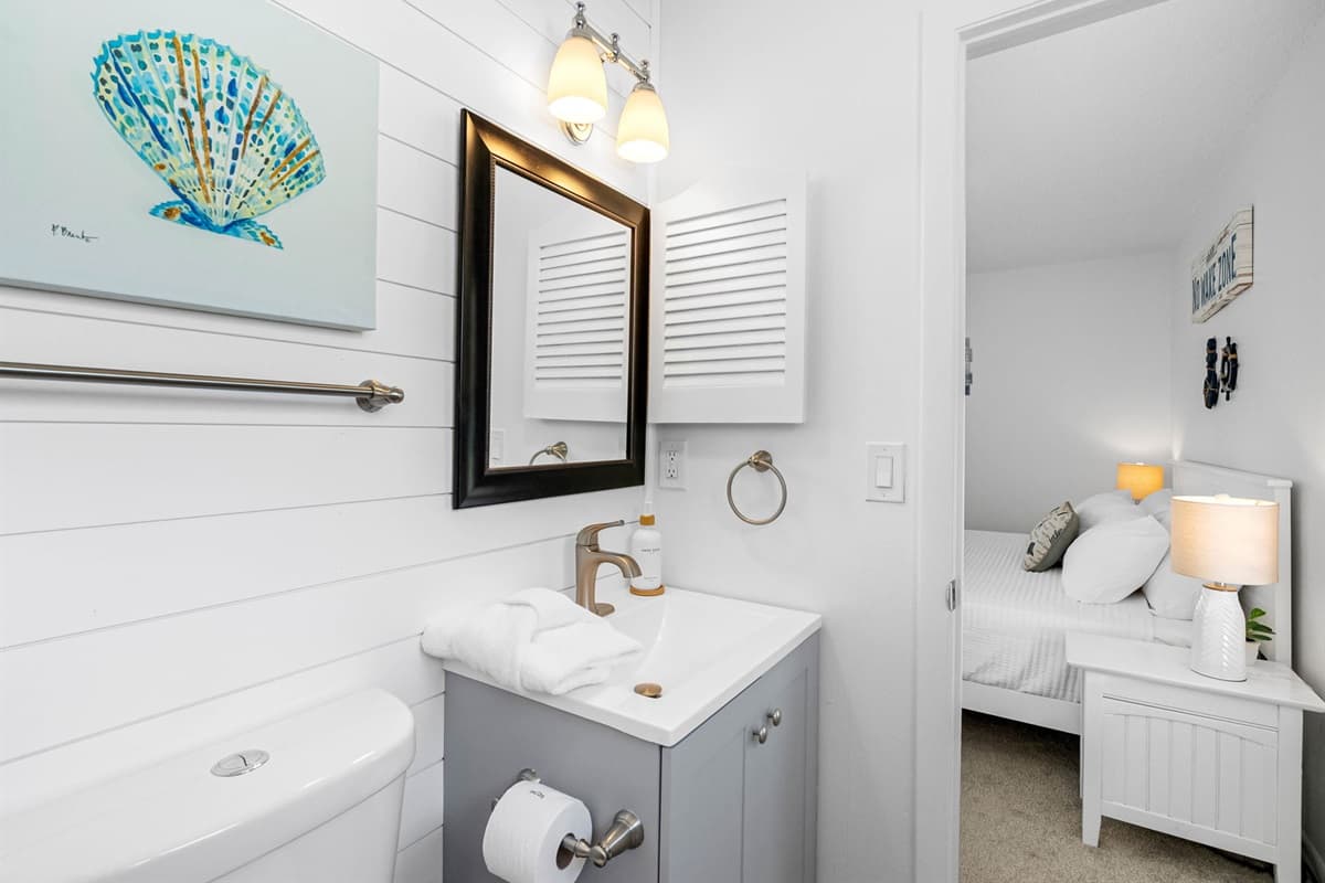 Bright and fresh with shiplap walls, ocean-themed artwork, and a sleek vanity, this bathroom brings coastal charm indoors.