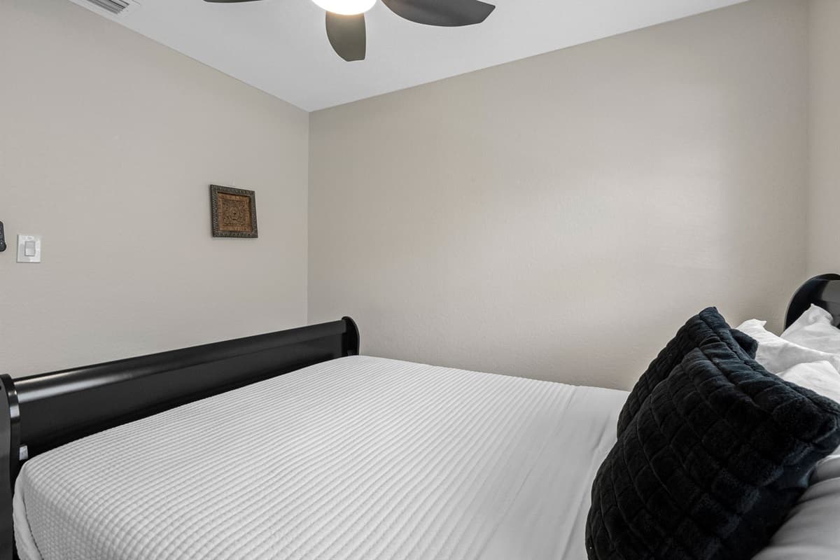 The full-size mattress is dressed in crisp white bedding, topped with two plush black accent pillows for a touch of texture and contrast.