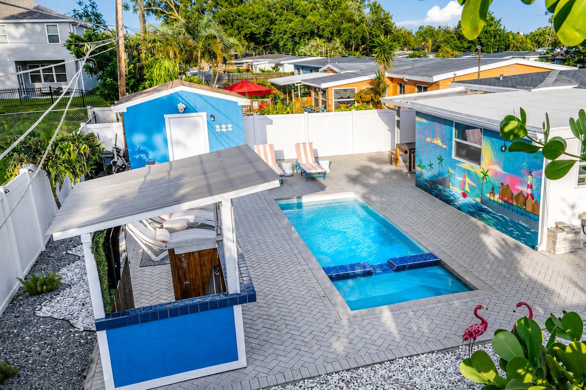 Elevated aerial-style view of the backyard oasis showcasing the pool, spa, outdoor bar, dining area, and surrounding amenities.