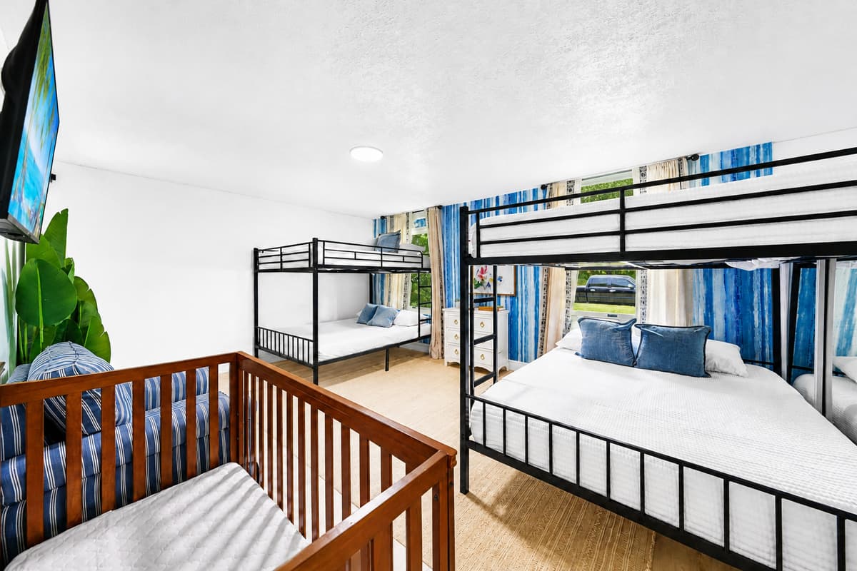 Bright window at the end, curtains open, four bunks lined up. Nobody sleeps in a dark corner.