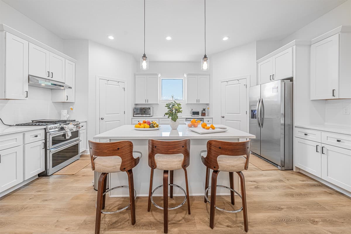Bright kitchen with island seating, stainless steel appliances, and clean, modern finishes.