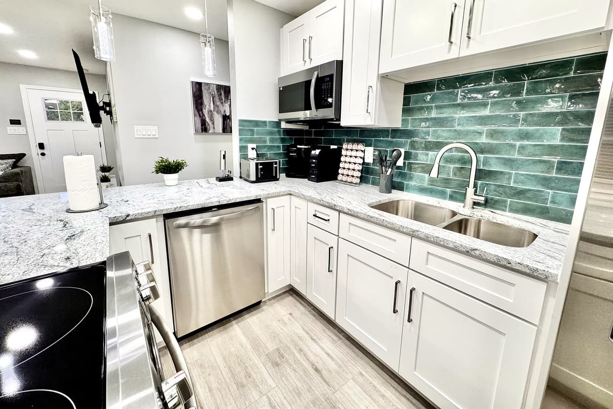 The sleek, polished countertops provide ample space for meal prep, while the thoughtfully arranged cabinetry is stocked with all the essentials, from pots and pans to baking sheets and cooking utensils.