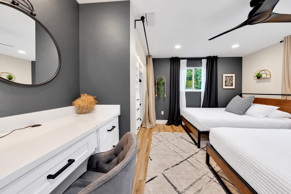 Enough drawers that the suitcases stay closed. Long dresser, mirror and two queen beds in a calm, uncluttered room — designed for the group members who arrive with the most luggage and the least patience.