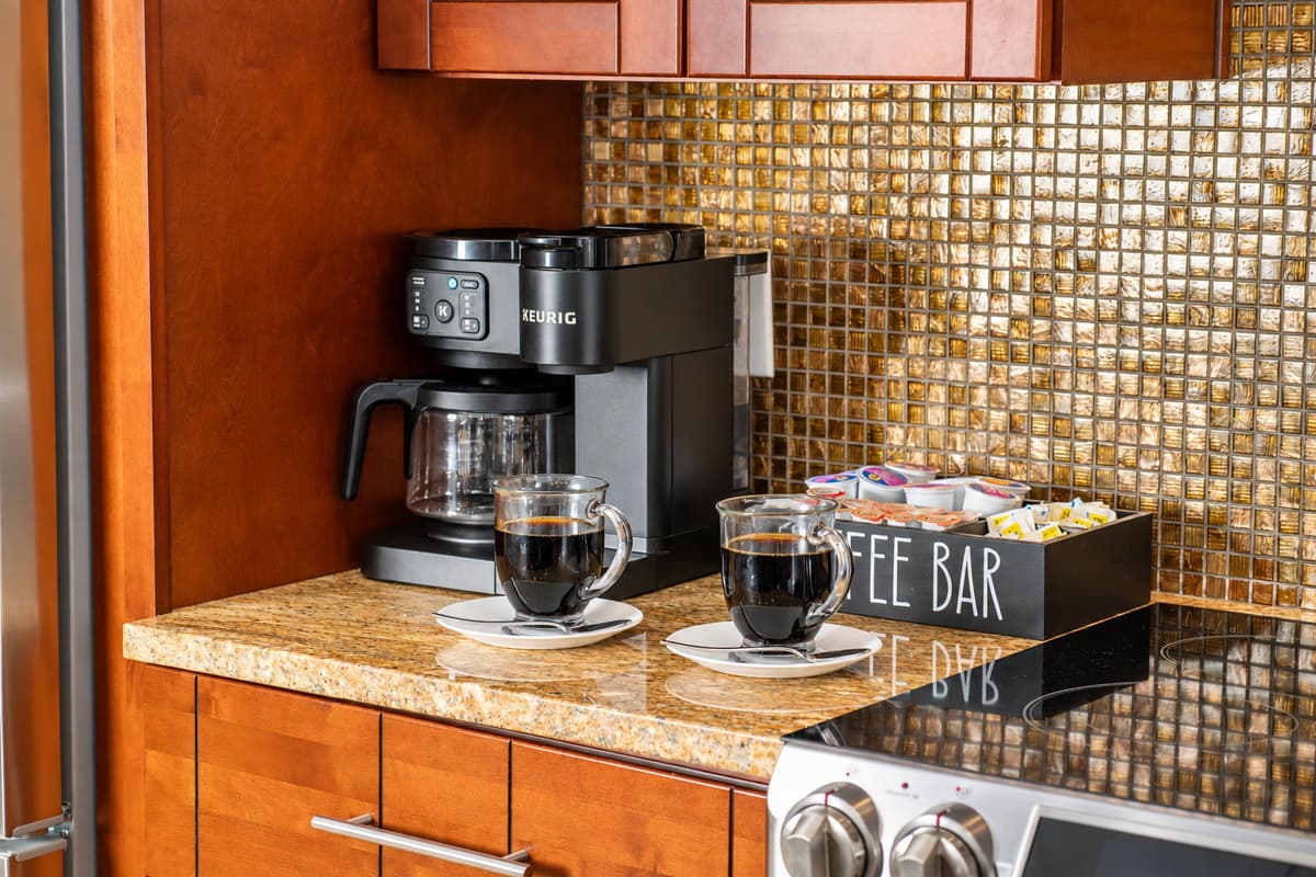 A dedicated coffee bar with a Keurig machine and mugs adds a cozy, personal touch to this polished kitchen.