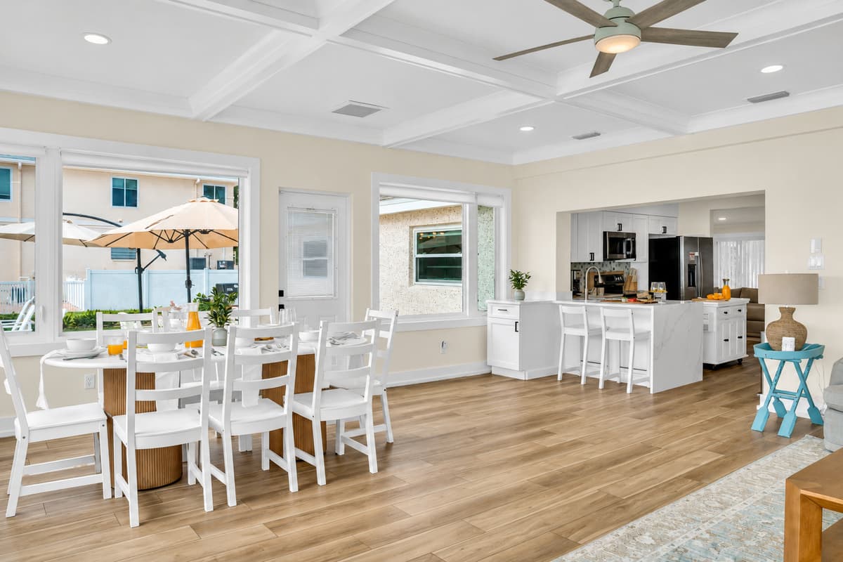 Round table, room for everyone. The dining area seats the group around a white round table, with the kitchen and bar stools close by. Meals feel easy and social.