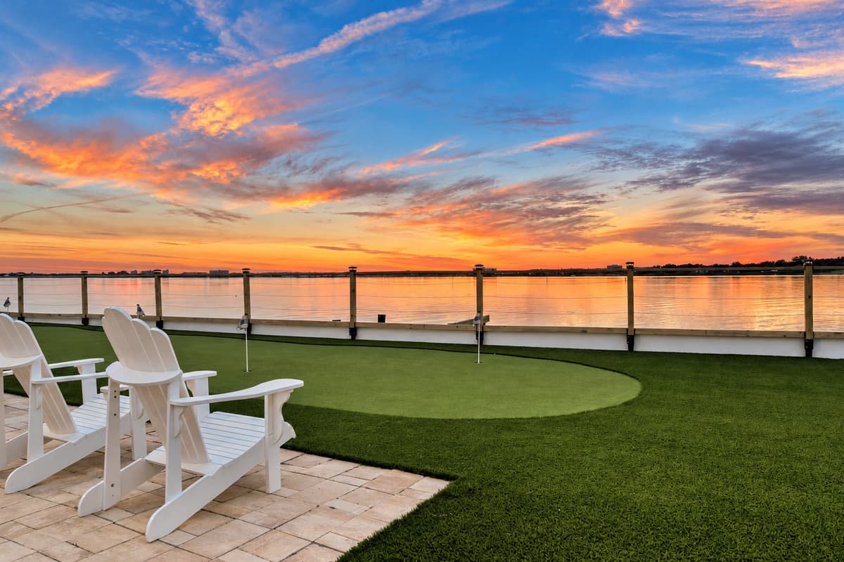 Adirondacks, putting green, sunset. Two chairs, a turf green and a sky on fire over the water. The kind of evening that becomes the highlight of the trip.