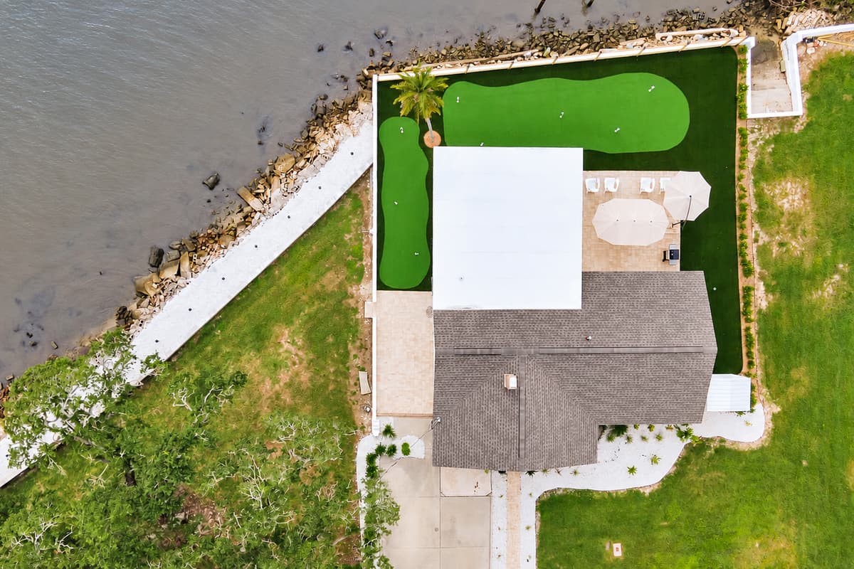 A bird's-eye view of your putting green. From above you can see the full green, patio and seawall on the bay. The kind of backyard that turns a stay into a story.