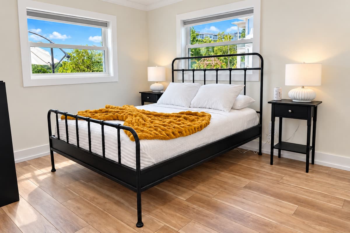 Queen bedroom with a black metal bed frame and mustard throw.