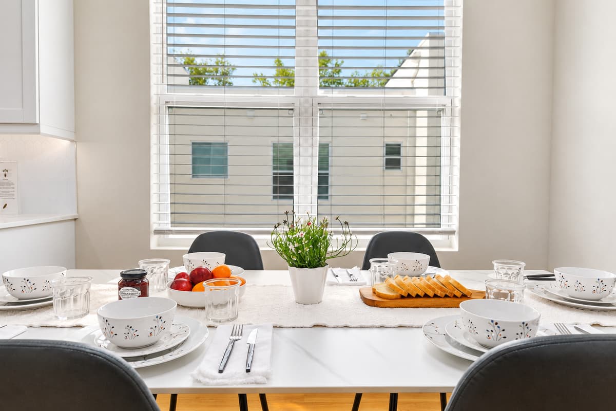 Bright dining table by large windows with natural light and modern table setting.