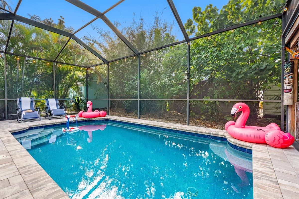 Relax by the crystal-clear pool in a private, screened-in setting surrounded by mature tropical plants.