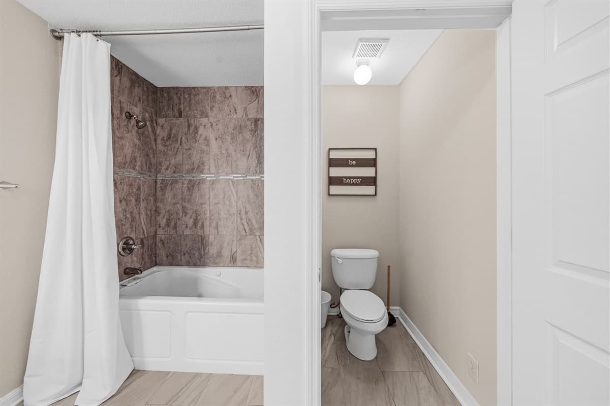 Clean and functional bathroom featuring a tub/shower combo and private toilet area.