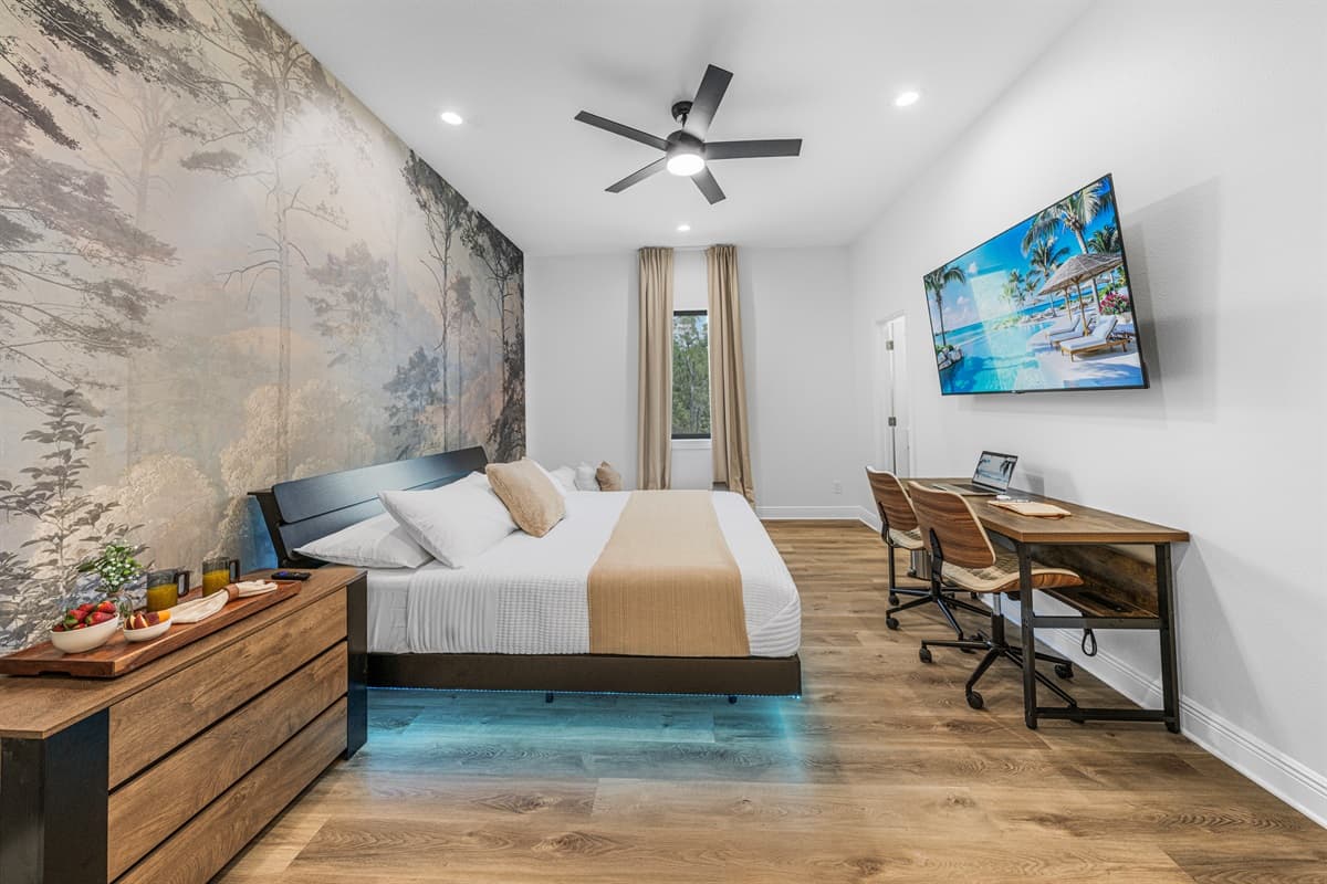 Spacious primary bedroom featuring a king bed, ambient lighting, and a beautiful nature-inspired accent wall.