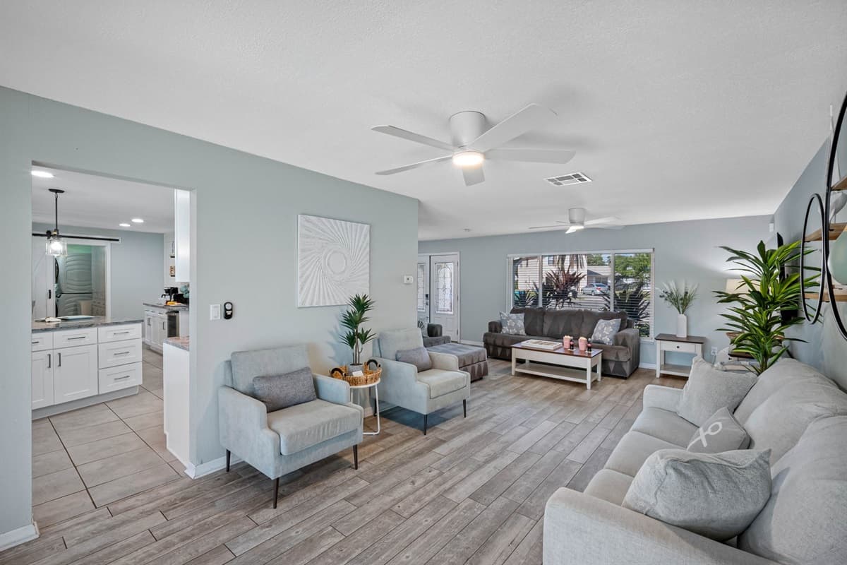 This open-concept living room offers plenty of seating, natural light, and direct access to the pool area for easy indoor-outdoor living.