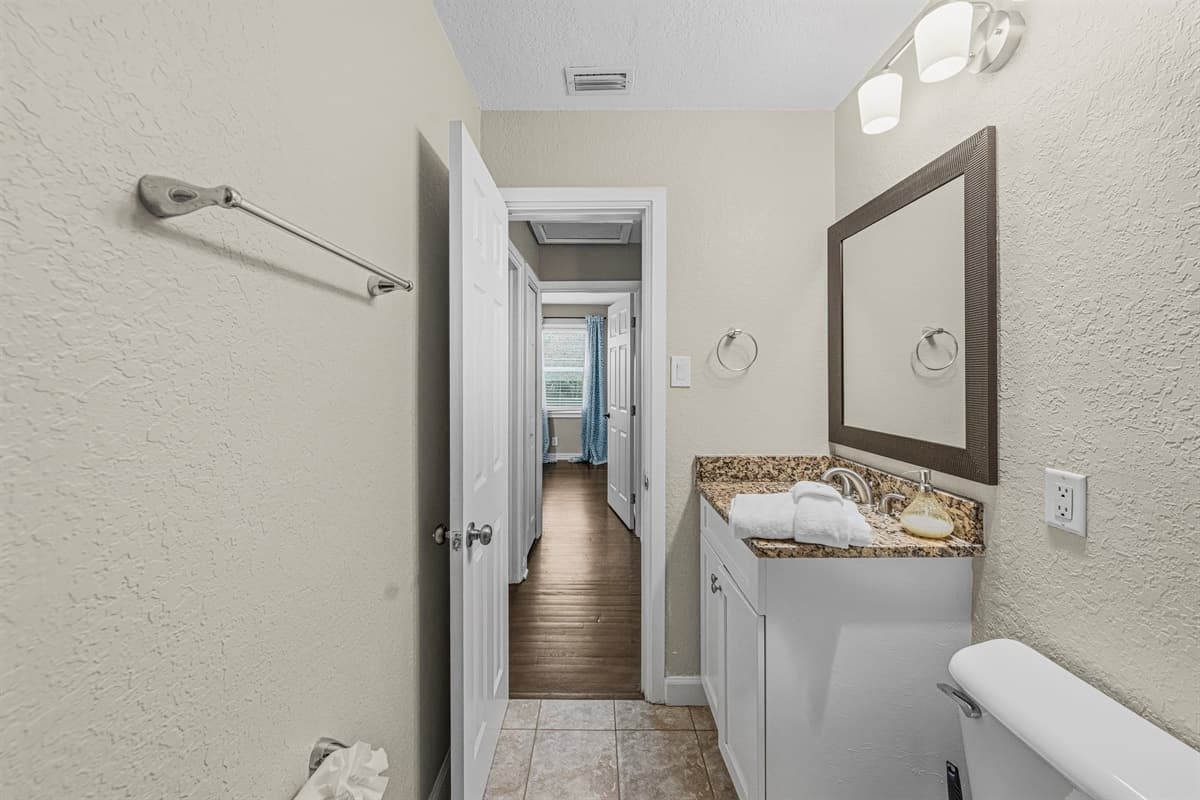Bathroom vanity area with mirror and storage, conveniently located near bedrooms.