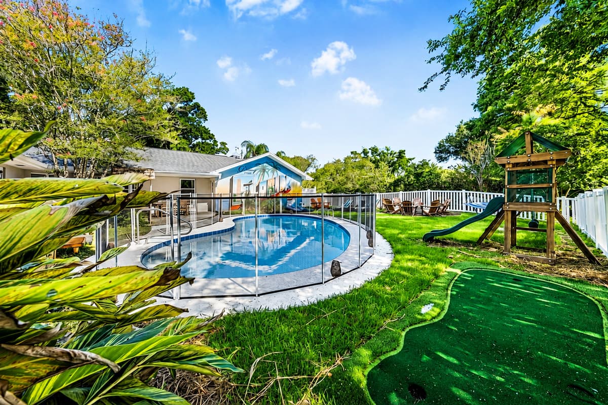 Hot tub in the foreground, pool in the middle, playground at the back. The yard keeps going.