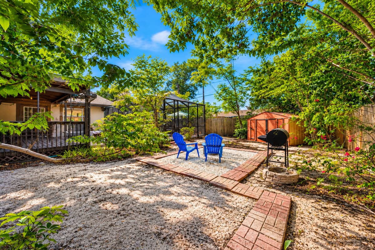 Spacious backyard retreat featuring shaded outdoor seating, a grill area, and relaxing natural landscaping.