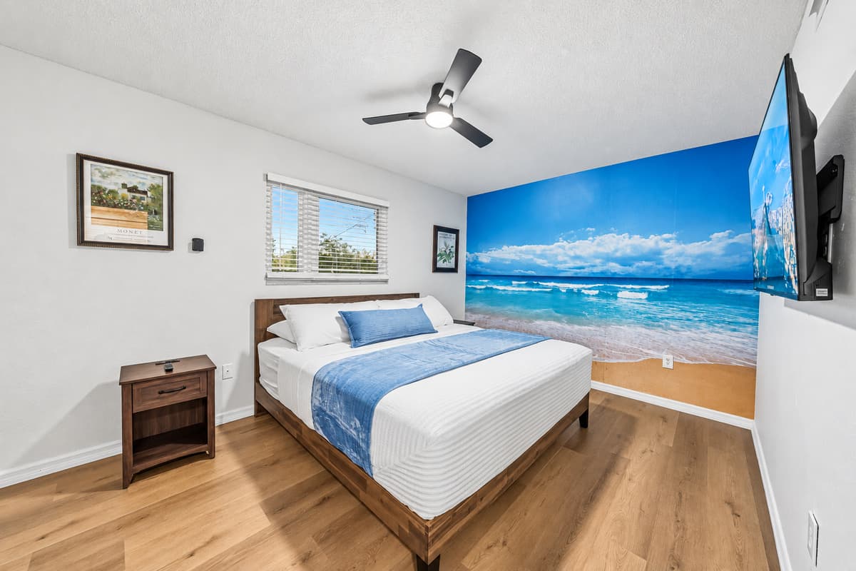 Relaxing bedroom retreat with beach mural and soft tones, perfect for a peaceful getaway 