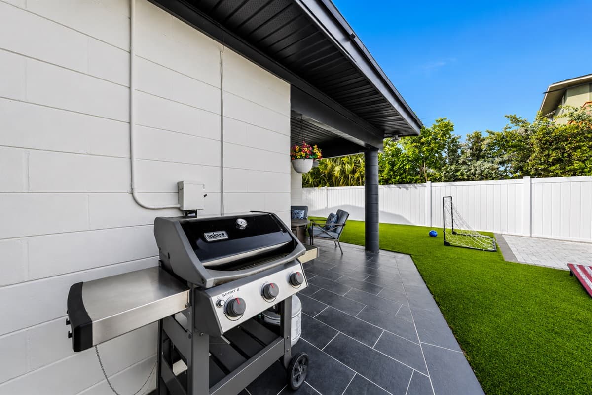 Gas grill setup conveniently located beside the covered patio and backyard lawn.