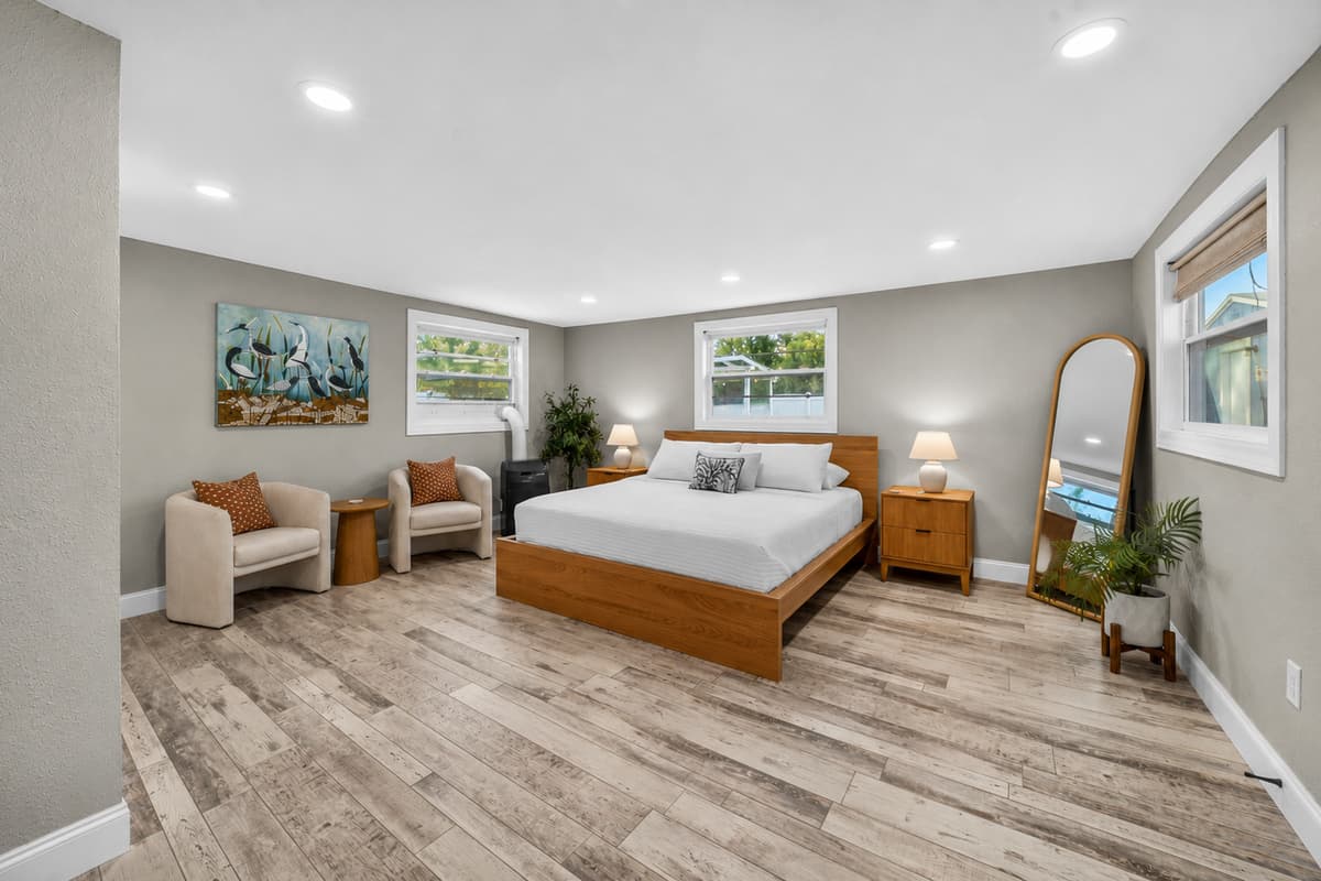 Wide-angle view of the primary suite showcasing ample floor space, comfortable seating, and relaxing neutral tones.