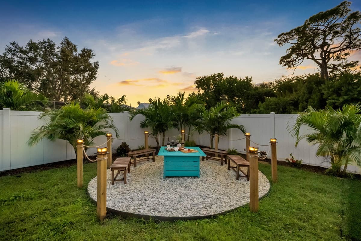 Enjoy the private, tropical backyard complete with a hammock, firepit lounge, and charming string lights for a magical nighttime glow.